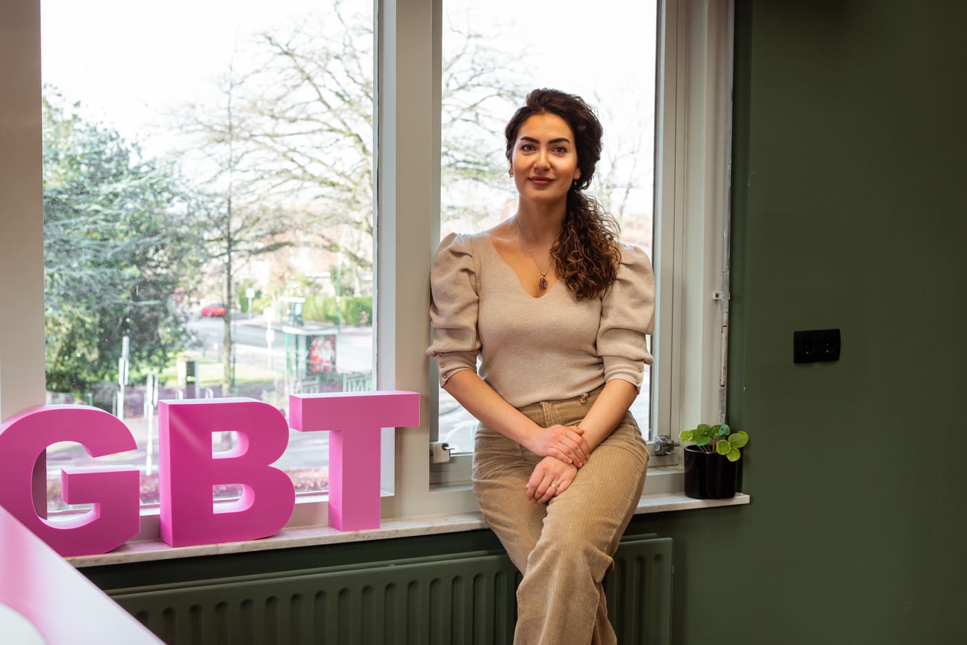 Medewerker bij het raam van de praktijk, naast roze letters die GBT vormen