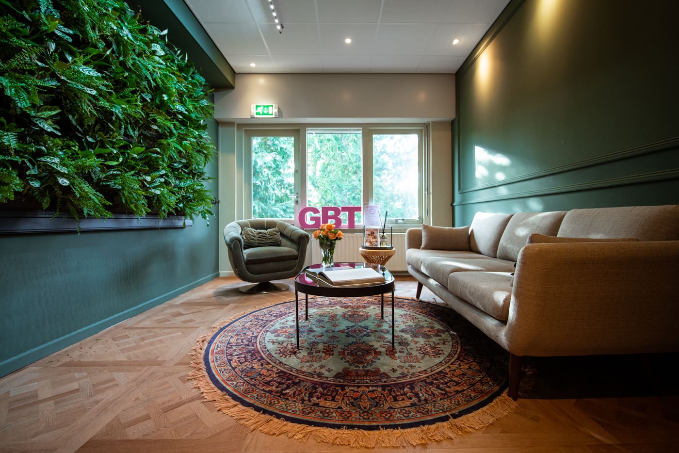 De Spa Lounge met bank, plantenwand en roze GBT-letters
