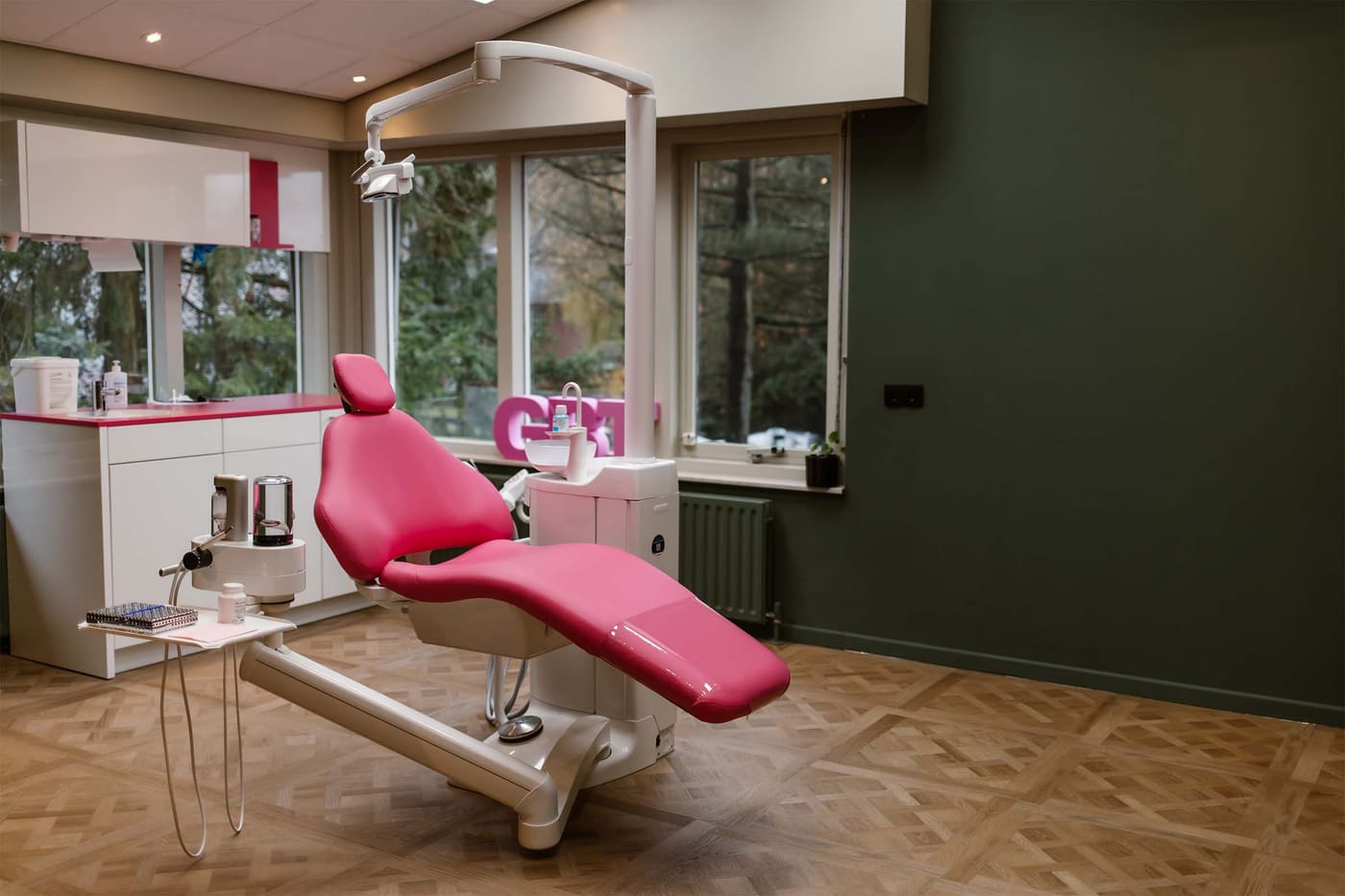 Behandelkamer met roze behandelstoel bij het raam